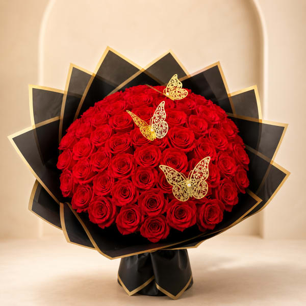 Large bouquet of red roses wrapped in black paper with gold trim and butterfly accents