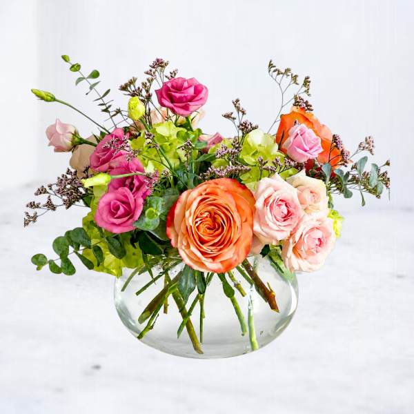 Mixed bouquet of roses and hydrangeas in a clear glass vase
