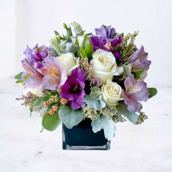 Purple and white bouquet in a square glass vase