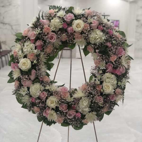 Large floral wreath of pink and white roses on a stand