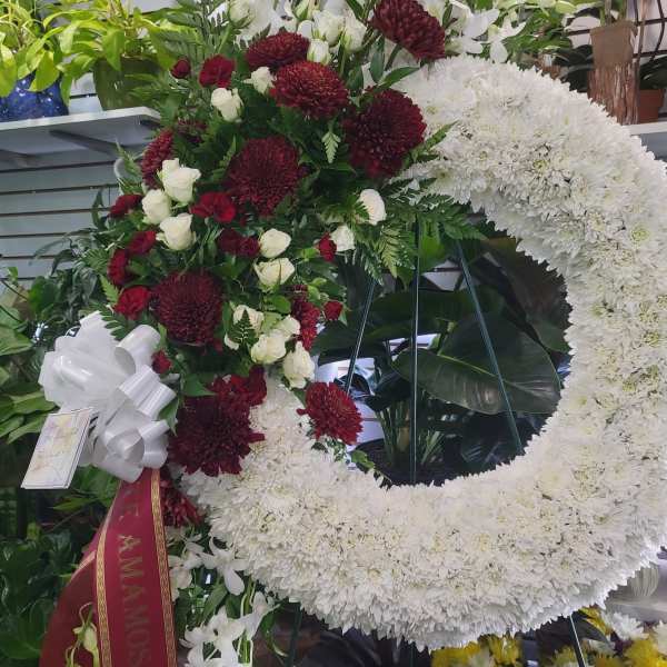 Large funeral wreath of white and burgundy flowers with a ribbon
