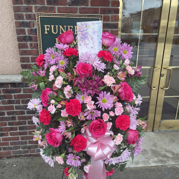 Large pink floral standing spray with roses, daisies, and carnations on an easel