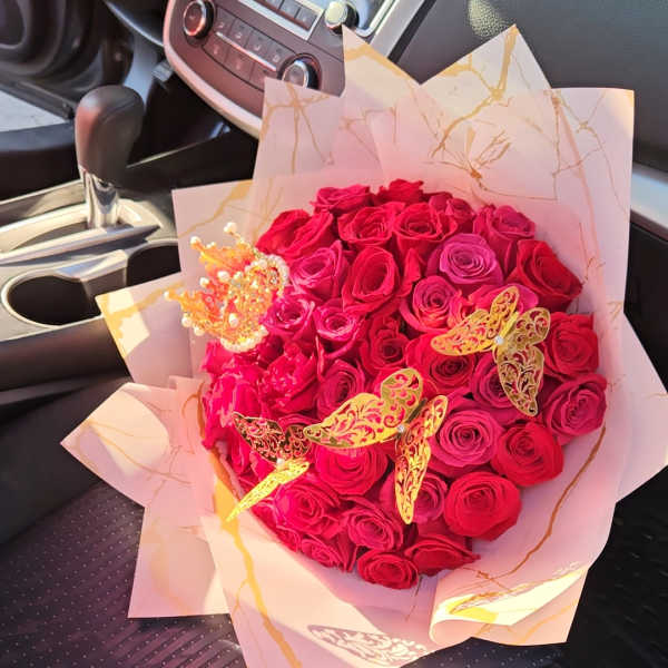 Heart-shaped bouquet of red roses with decorative butterflies in pink wrap