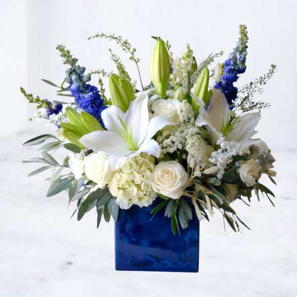 White lilies and roses in a blue square vase