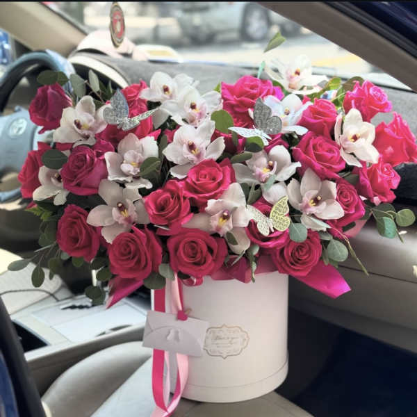 Pink roses and white orchids in a white hatbox with ribbon