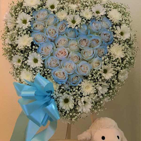 Heart-shaped bouquet of blue roses and white daisies with a blue ribbon