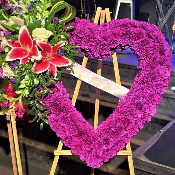 Heart-shaped floral tribute on an easel with pink flowers and lilies