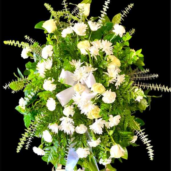 White flowers and greenery arranged on a standing easel with a ribbon