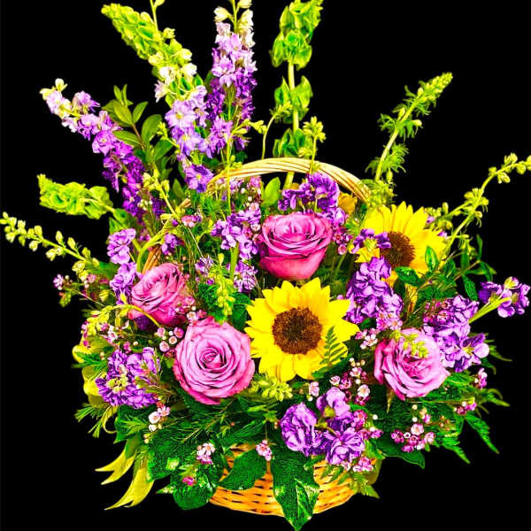 Basket arrangement with pink roses, sunflowers, and purple flowers