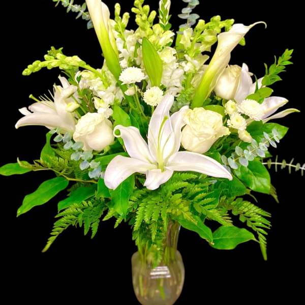 White lilies and roses arranged in a glass vase