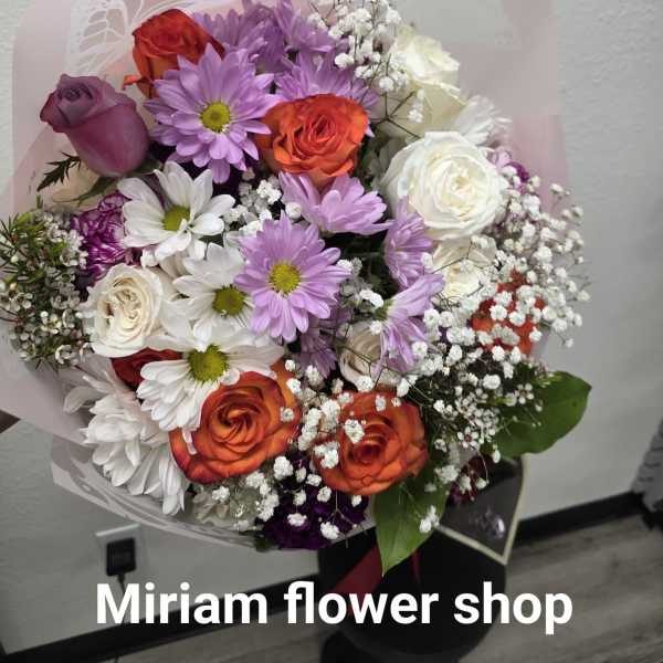 Mixed bouquet of roses and daisies wrapped in pale pink paper