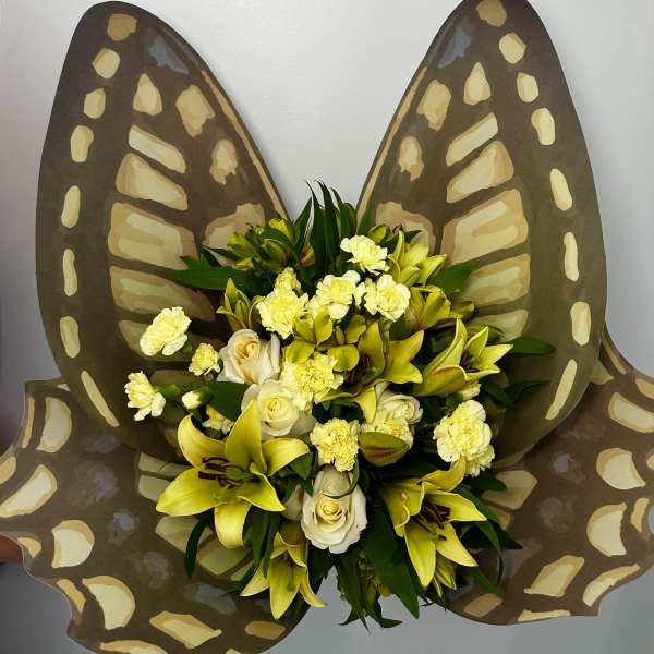 Yellow lilies and white roses arranged with butterfly wings behind them