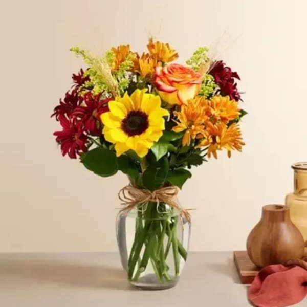 Mixed bouquet of sunflowers, roses, and chrysanthemums in a glass vase