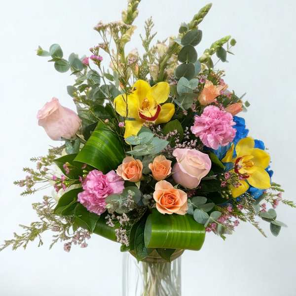 Mixed bouquet of roses, orchids, and carnations in a glass vase