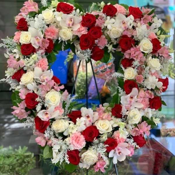 Heart-shaped floral wreath with red, white, and pink roses and orchids