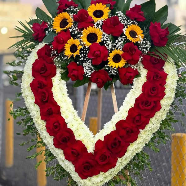 Heart-shaped floral wreath with red roses, white flowers, and yellow sunflowers