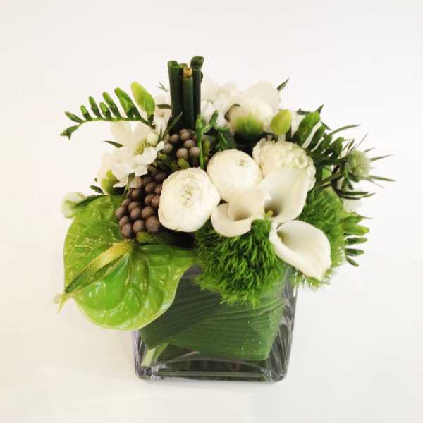 White flowers and green accents arranged in a square glass vase