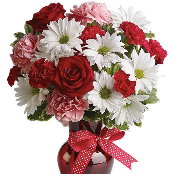 Bouquet of red roses, pink carnations, and white daisies in a red vase with a ribbon