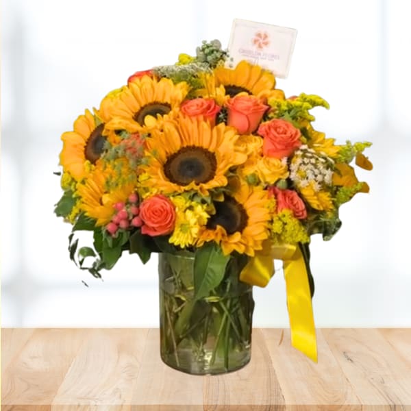 Sunflower and rose bouquet in a glass vase with a yellow ribbon