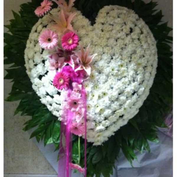 Heart-shaped white floral wreath with pink flowers and ribbon accents