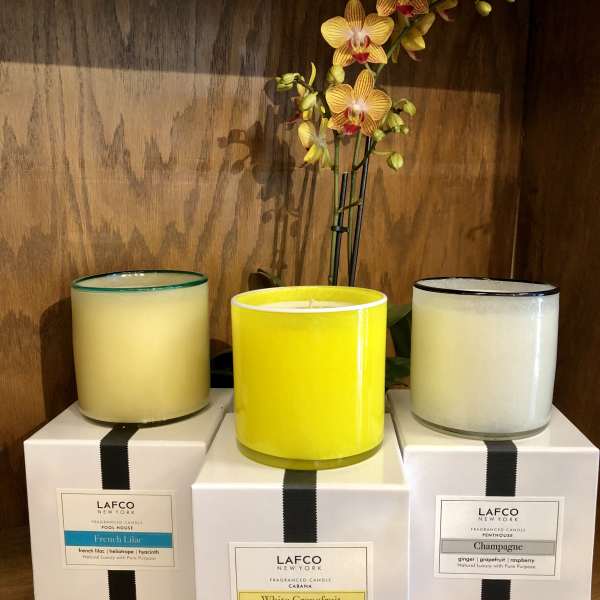 Three scented candles with an orchid stem behind them