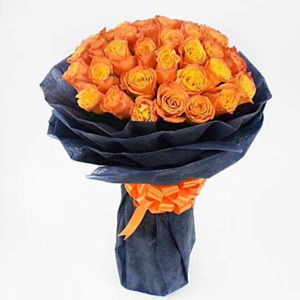 Bouquet of orange and yellow roses wrapped in dark paper with an orange ribbon