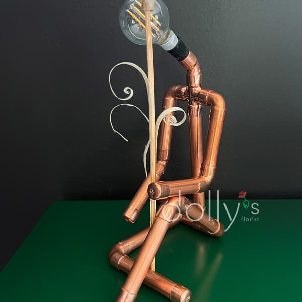 Copper pipe figure holding a white flower with a light bulb head
