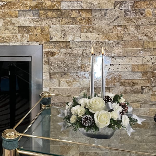 White rose arrangement with candles in a low silver container