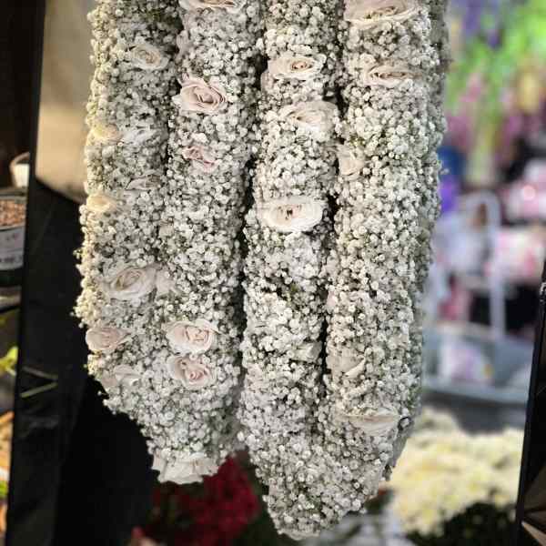 Four hanging floral garlands covered in white baby's breath with pale roses