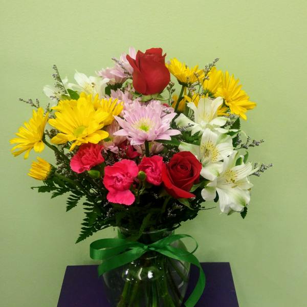 Mixed bouquet of roses, daisies, carnations, and alstroemeria in a glass vase