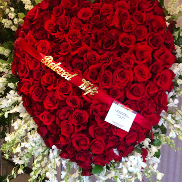Heart-shaped red rose funeral wreath with white flowers around it