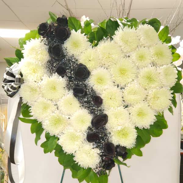 Heart-shaped white chrysanthemum wreath with black roses and ribbon