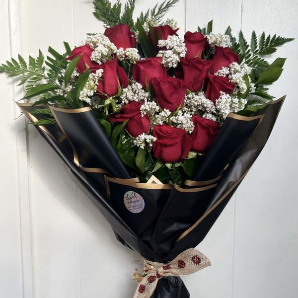 Bouquet of red roses with white filler flowers wrapped in black paper