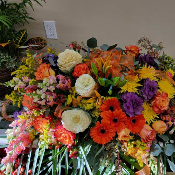 Large colorful floral arrangement with roses, gerbera daisies, and ribbon