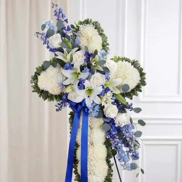 White floral standing spray with blue accents and a blue ribbon
