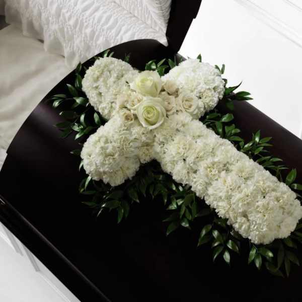 White floral casket spray with roses and carnations on a dark casket