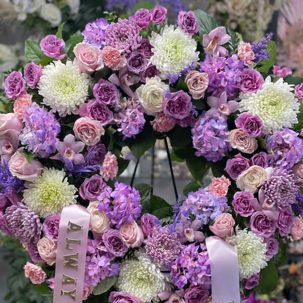 Heart-shaped floral wreath with pink and purple blooms and satin ribbons