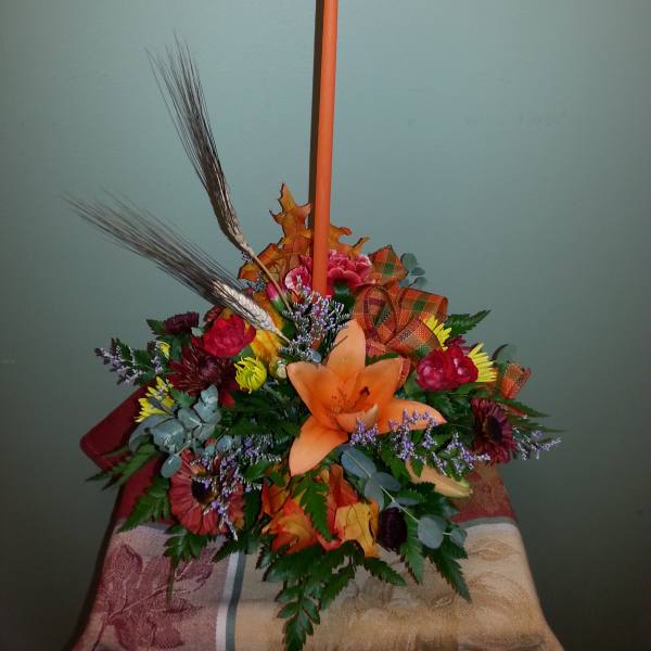 Autumn floral arrangement with an orange taper candle and mixed flowers