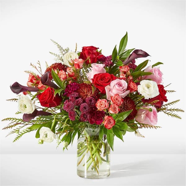 Mixed bouquet of red, pink, and white flowers in a glass vase