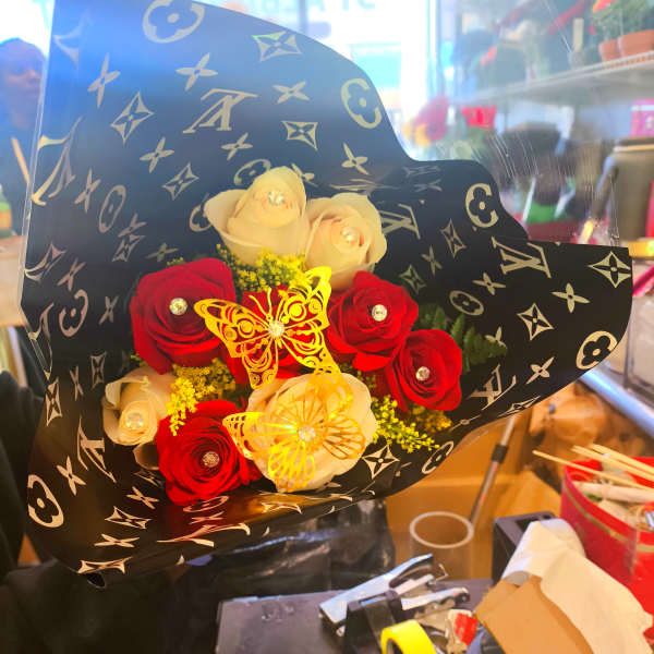 Bouquet of red and cream roses wrapped in black patterned paper
