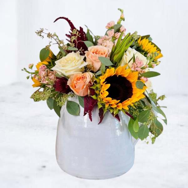 Mixed bouquet with sunflowers and roses in a white vase