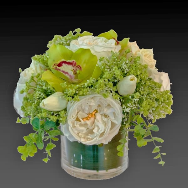 White and green floral arrangement in a clear glass vase with orchids and roses