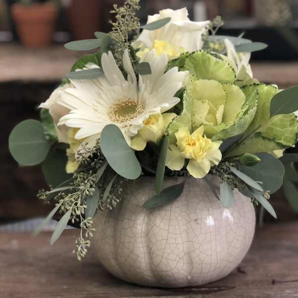 White and pale yellow floral arrangement in a round ceramic vase
