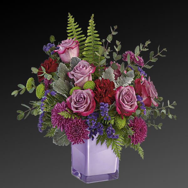 Purple roses and mixed blooms in a lavender glass vase