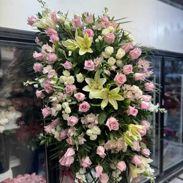 Large standing spray of pink roses and pale lilies