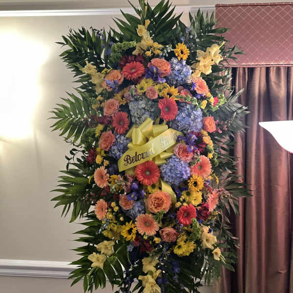 Large standing floral spray with a yellow ribbon and mixed blooms