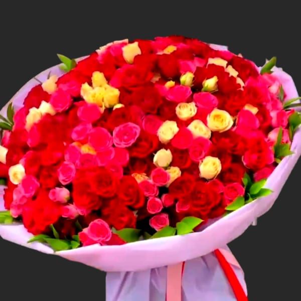 Large bouquet of red, pink, and yellow roses wrapped in white paper
