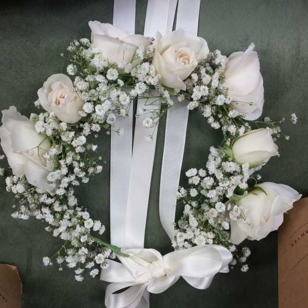 White rose floral wreath with baby's breath and a white ribbon bow