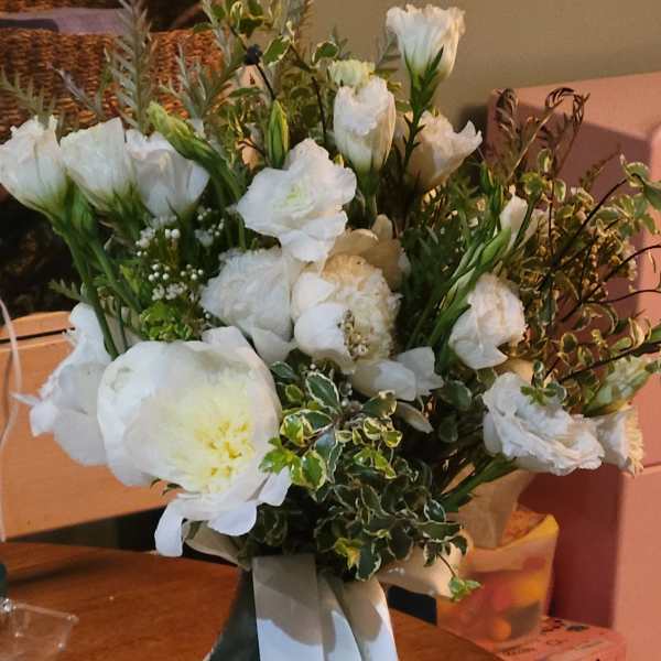 White bouquet with peonies and tulips tied with long white and green ribbons