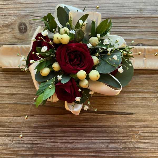 Red rose bouquet with white berries and ribbon on a wooden surface